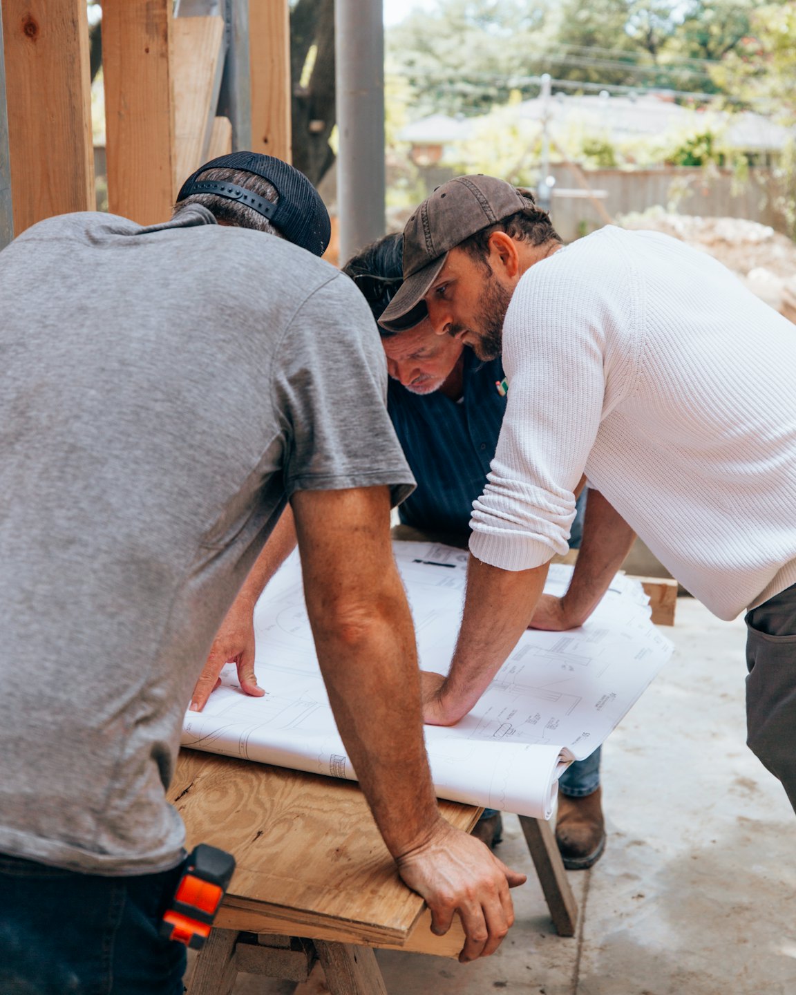 Construction workers review blueprints at an outdoor site.