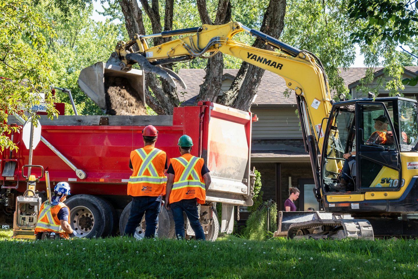 Construction workers load dirt into a dump truck at a worksite.