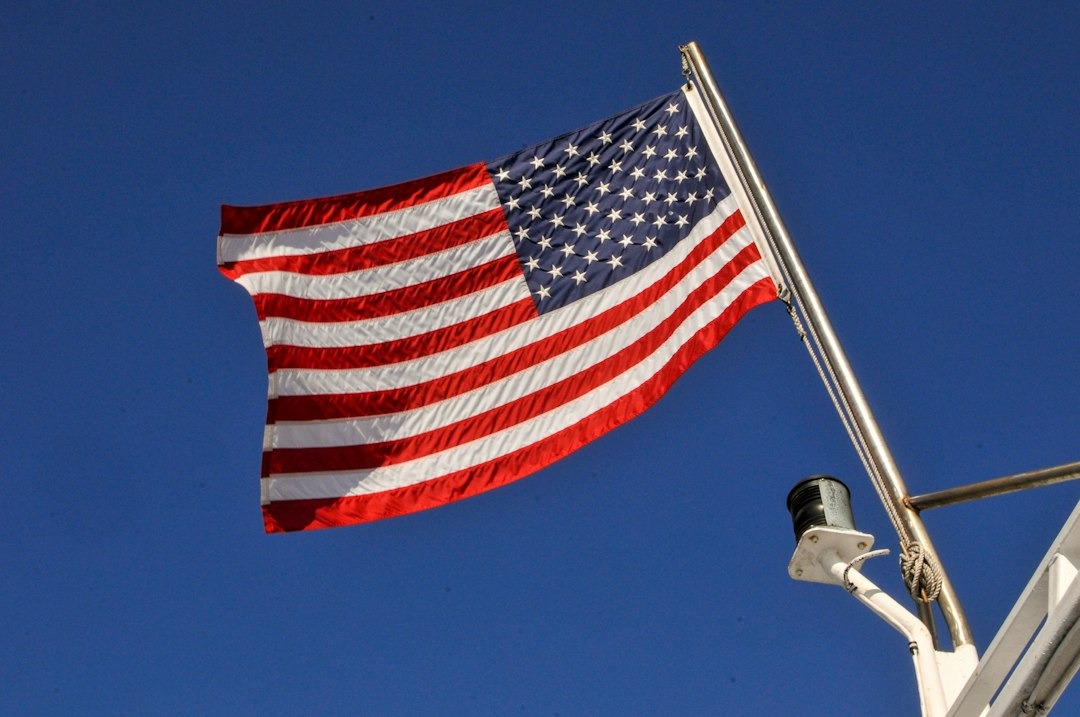 American flag waving on a boat mast against a clear sky.
