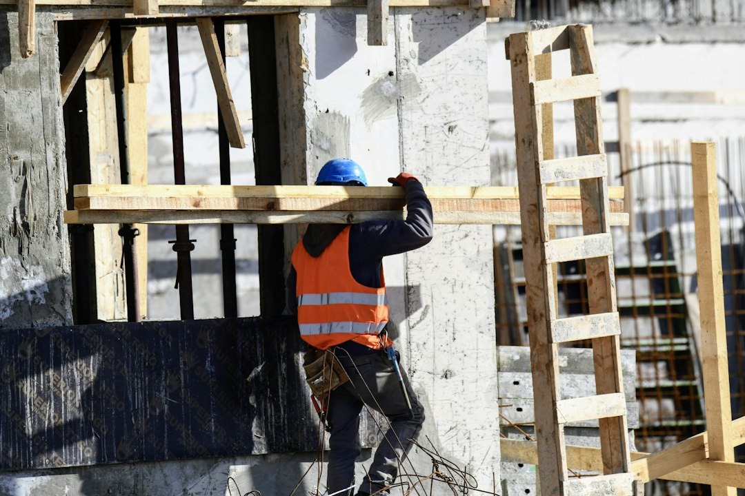 Construction workers review blueprints at an unfinished site.